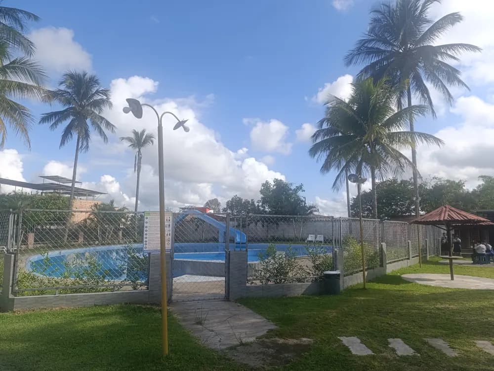 Piscina del campus, cercada, con la zona de descanso al costado.