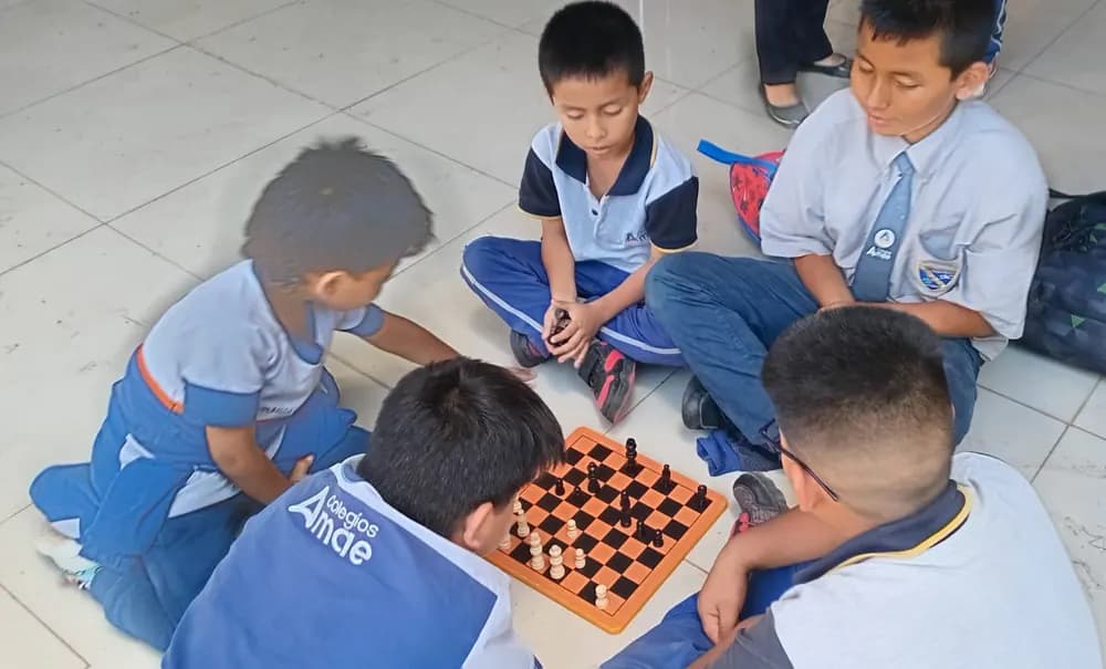 Un grupo de alumnos jugando ajedrez en el suelo durante el recreo.